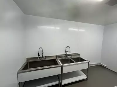 Empty washroom with stainless steel sinks before pipework and hose point installation at a manufacturing facility in Nottingham.